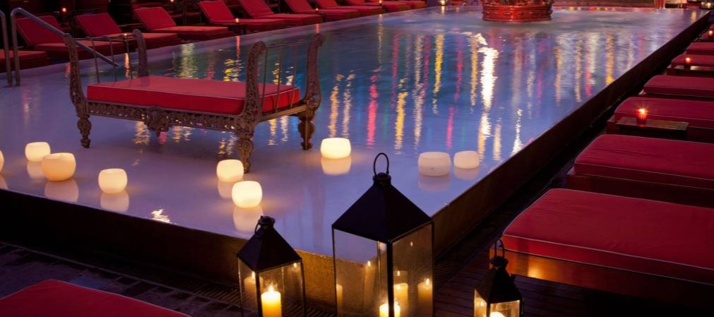 Chic poolside at Faena Hotel Buenos Aires, with red loungers, glowing lanterns, and a crown fountain under colorful lights