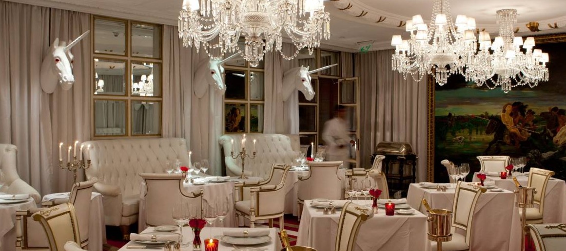 Opulent dining room at Faena Hotel Buenos Aires with crystal chandeliers, white banquettes, and whimsical unicorn décor creating a luxurious fairy-tale atmosphere
