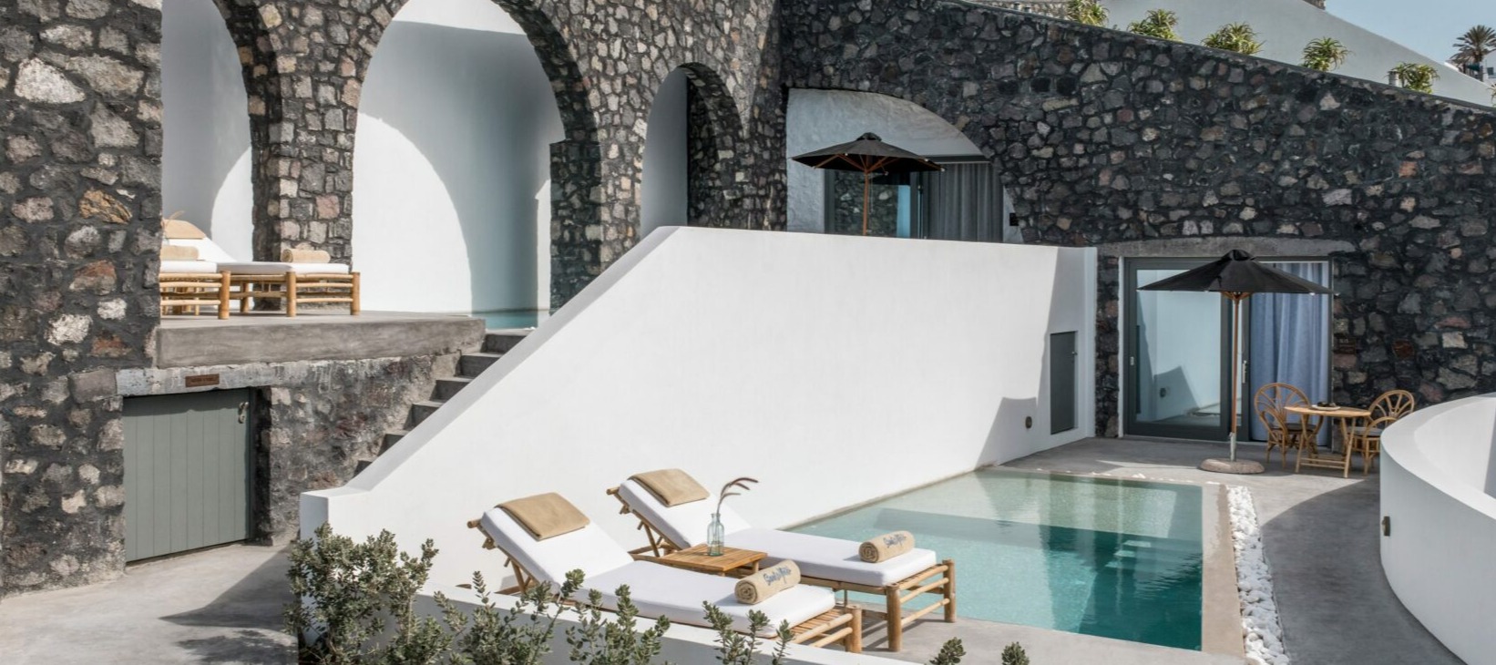 Private villa terrace with pool, stone arches, and white Cycladic architecture