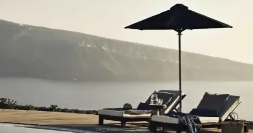 Poolside loungers with umbrella overlooking Santorini caldera 