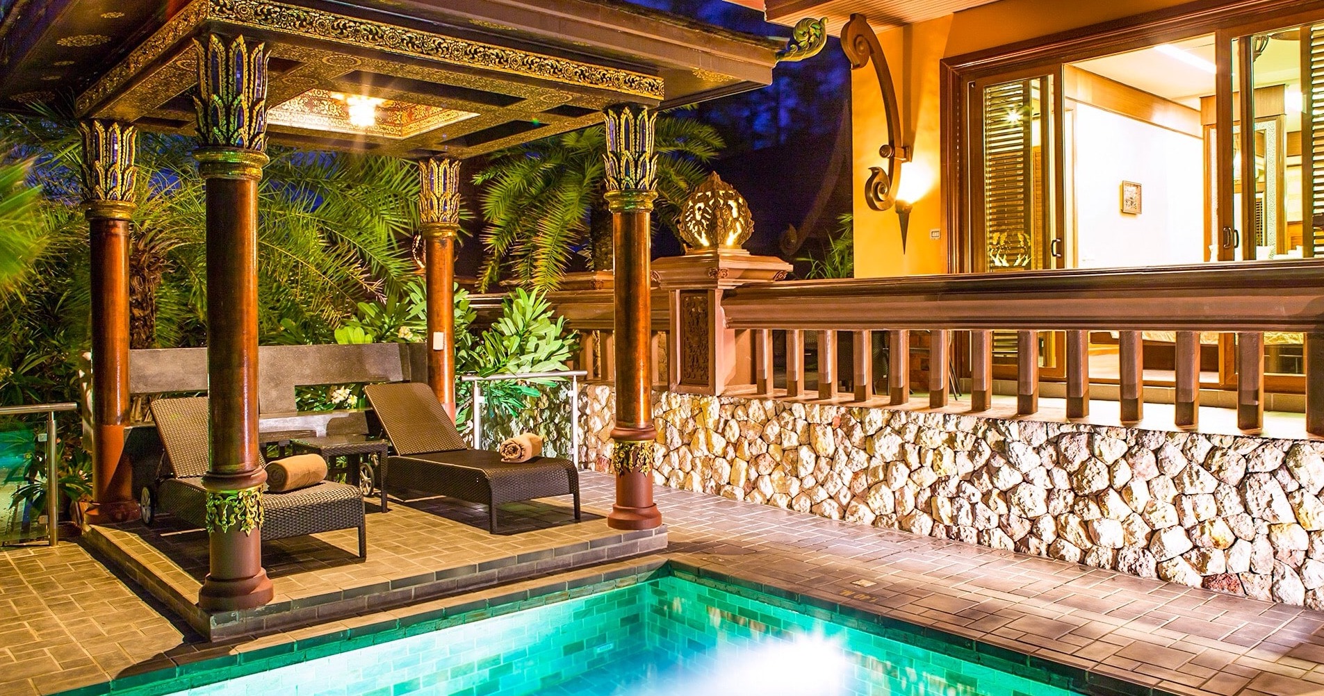 Illuminated Thai-style villa with private pool at twilight