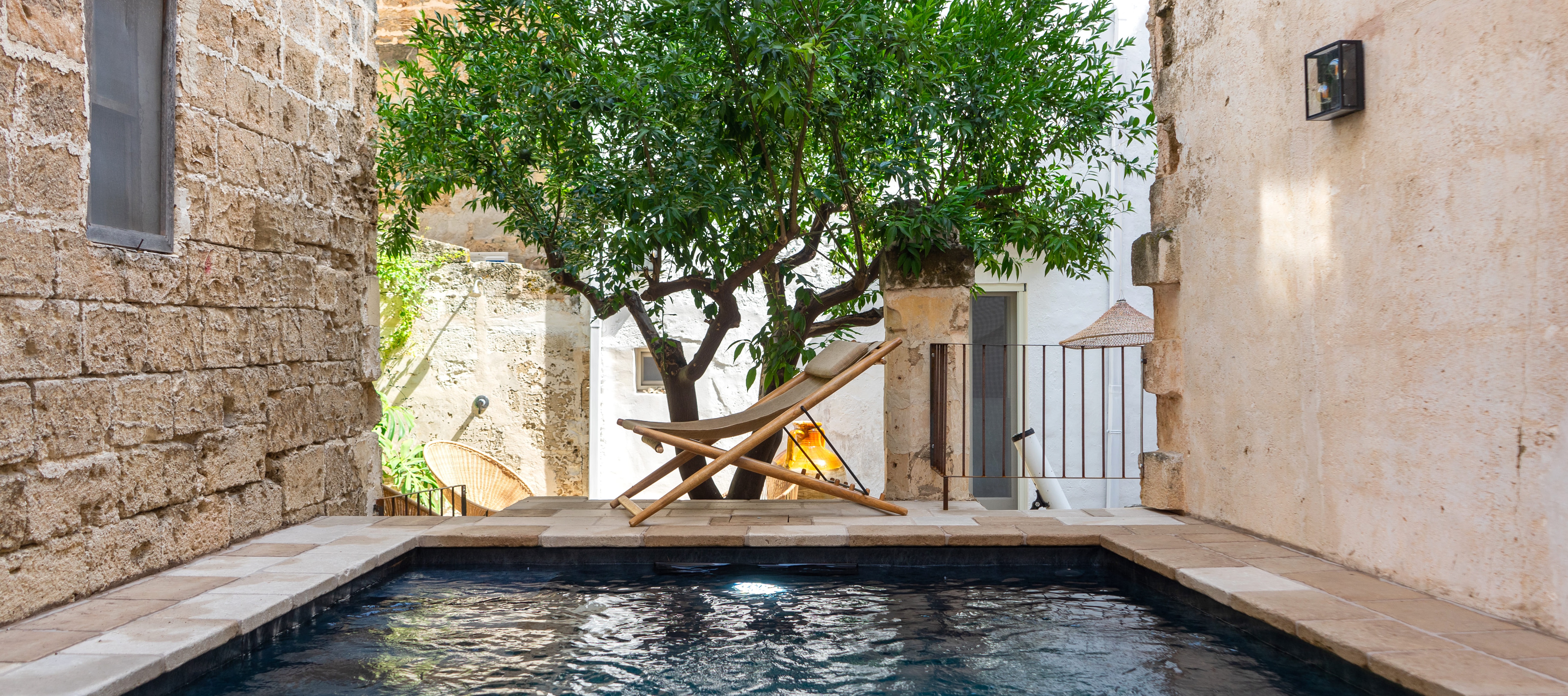 Intimate courtyard pool with stone walls and olive tree