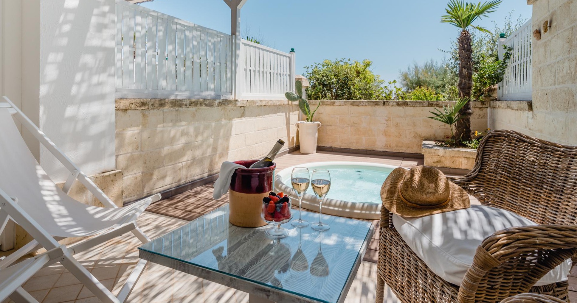 Private terrace with plunge pool, champagne, wicker furniture, and palm trees