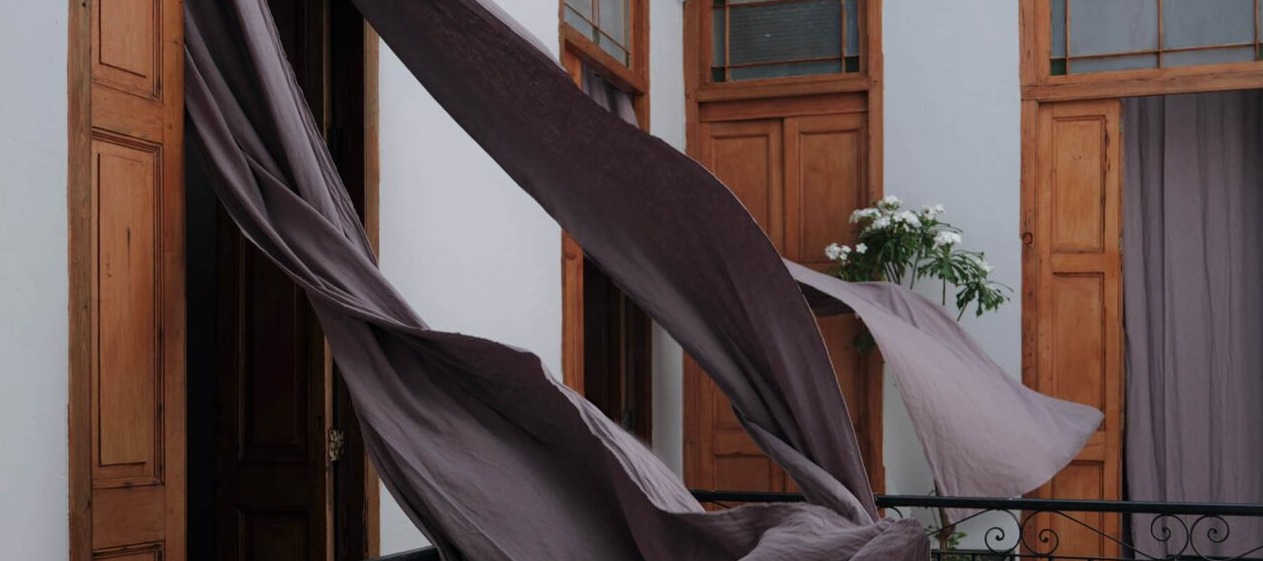 Sheer curtains billowing from balcony with wooden doors and flowers