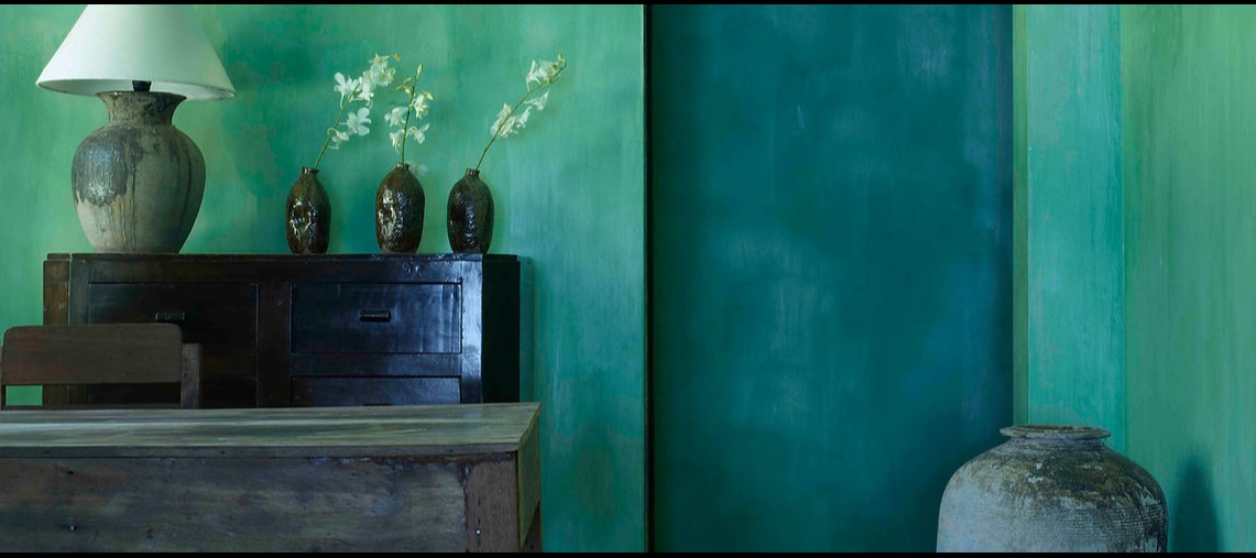 Turquoise wall featuring antique Thai ceramics and vintage wooden furniture